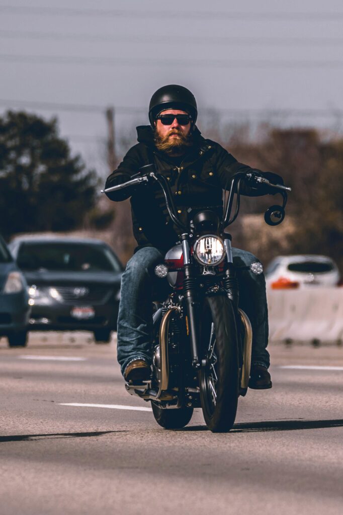 pexels-photo-2056949-2056949 Bearded man riding a motorcycle on a busy urban highway, showcasing speed and style.